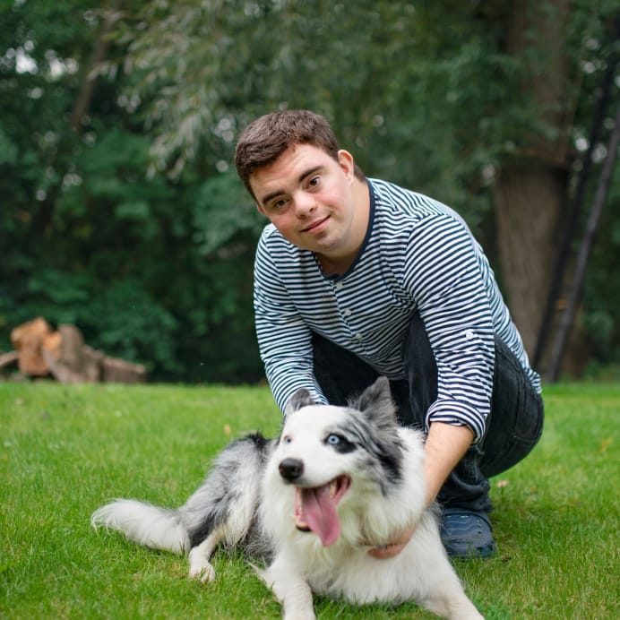 Happy man petting a dog on grass